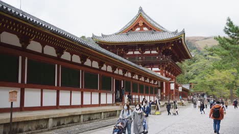 Exterior-of-Todaiji-Temple-in-Nara,-Tourists-Walk-in-Slow-Motion-Wearing-Masks