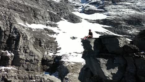 Man-sits-by-himself-resting-on-the-mountainside-with-protective-climbing-gear