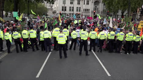 Polizisten-Der-Londoner-Metropolen-Stehen-An-Einer-Absperrung-Schlange,-Während-Sie-Einen-Protest-Gegen-Den-Klimawandel-überwachen,-Der-Die-Straße-Vor-Dem-Parlament-In-Westminster-Blockiert-Hat