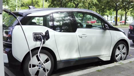 Estación-De-Carga-Ecológica-Con-Coche-Eléctrico-Moderno-Junto-A-La-Carretera