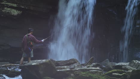 A-fisherman-casts-his-fishing-rod-below-Seneca-Falls,-a-large-waterfall-located-along-Seneca-Creek,-within-the-Spruce-Knob-Seneca-Rocks-National-Recreation-Area-in-West-Virginia