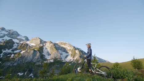 Mountainbiker-Hält-An,-Um-Bei-Sonnenaufgang-Von-Einem-Bergrücken-Aus-Auf-Den-Abrupten-Hügel-Zu-Blicken