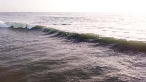 Gente-Surfeando-En-La-Playa-Ondulada-De-Olón-En-Ecuador-Al-Atardecer--Antena