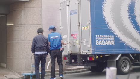 Delivery-Man-Closed-The-Door-Of-Sagawa-Express-Delivery-Truck-While-Talking-To-A-Customer-In-Front-Of-A-Building-In-Tokyo,-Japan