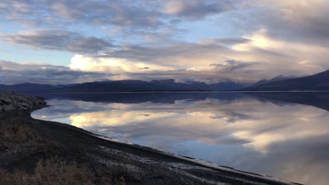 Kluane-lake-in-Canada-at-still-and-cloudy-sunset,-panning-long-shot