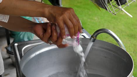 Motion-shot-woman-adding-salt-into-water-in-a-saucepan-on-outdoor-kitchen