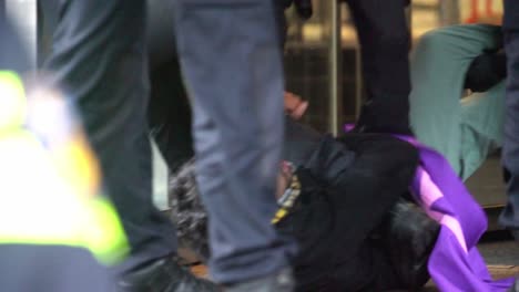 Police-arresting-young-caucasian-man,-protester-lies-on-ground,-protesting-against-climate-change-XR-protest,-handheld,-day