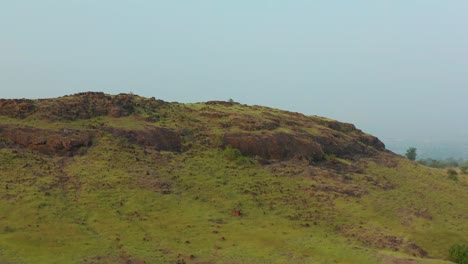 Paisaje-Brumoso-Revelado-Detrás-De-Una-Colina-Rocosa-Verde-En-India