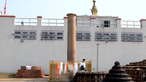 A-Security-personnel-passes-by-Maya-Devi-Temple-and-Asoka-pillar-in-Lumbini,-Nepal