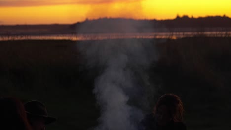 Hand-held-shot-of-silhouettes-standing-next-to-steam-rising-from-the-cooker-over-the-sunset