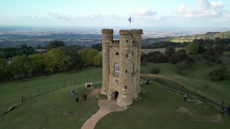 Low-aerial-orbit-shot-of-Broadway-tower,-an-English-landmark-stood-atop-Beacon-Hill-in-the-Cotswolds,-UK