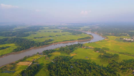 Winding-Surma-river-aerial-view-over-Bangladesh-agricultural-farmland-countryside-towards-misty-valley-horizon