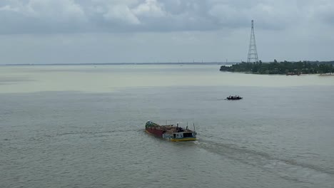 Dolly-shot-along-a-bridge-with-a-cargo-barge-sailing-through-river-in-Sylhet