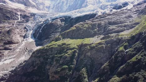Aerial-side-traveling-of-the-swiss-alps-with-a-glacier-and-awaterfall