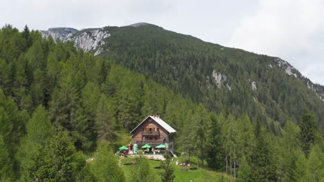Aerial-shot-of-remote-wooden-house-in-the-middle-of-forest-on-a-mountain
