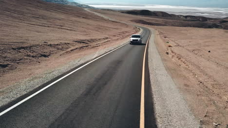 Aerial-Shot-Of-A-Tourist-Mini-Van-Driving-On-Desert-Highway,-National-Park-Landscape-In-California