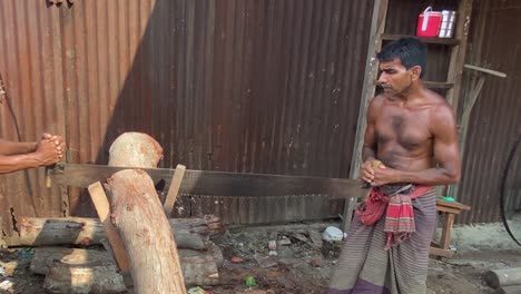 Slow-motion-shot-of-men-using-a-hand-saw-cutting-a-log-into-smaller-chunks