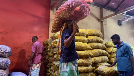 Tracking-shot-of-workers-lifting-bagged-produce-and-carrying-it-on-their-head