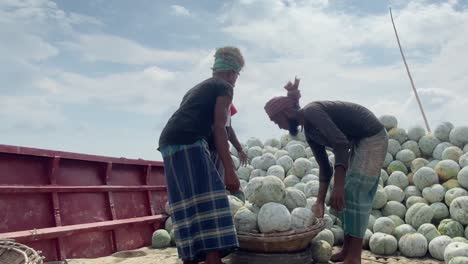 Hand-held-shot-of-people-loading-and-basket-and-lifting-it-onto-a-workers-head