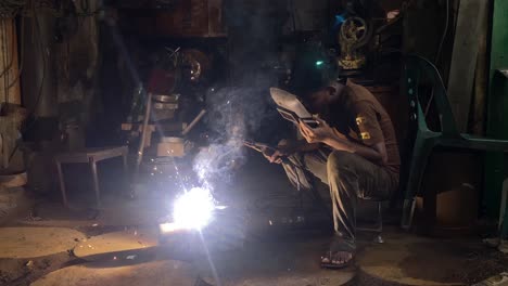 Hand-held-shot-of-a-young-man-welding-a-transmission-together-in-a-garage