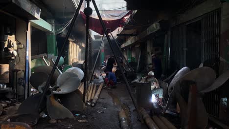 Arbeiten-In-Der-Werkstatt,-Schweißen-Von-Booten,-Riesiger-Ventilator,-Dhaka,-Bangladesch