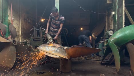 Toma-De-Mano-De-Un-Trabajador-De-Barco-Usando-Una-Amoladora-Angular-En-Una-Hélice-De-Barco-Grande