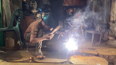 young-man-welding-in-a-messy-workshop-in-Dhaka,-Bangladesh