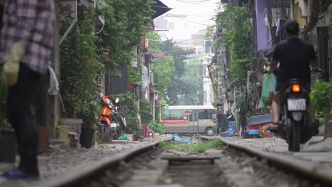 Daily-life-on-Train-Street-with-locals,-motorbikes-and-children-in-famous-Old-Quarter-in-Hanoi,-Vietnam