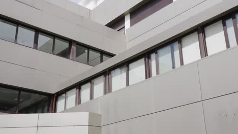 Quadratisches-Krankenhausgebäude-An-Einem-Sonnigen-Tag-Mit-Einer-Frau,-Die-Das-Fenster-Putzt.-Modernes-Gebäude