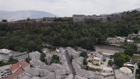 Fly-over-old-Gjirokastër-city-to-historic-ottoman-fortress,-Albania