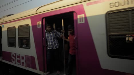 Tren-Local-Con-Gente-Sentada-Adentro-Y-Parada-En-La-Puerta,-Kolkata,-Bengala-Occidental