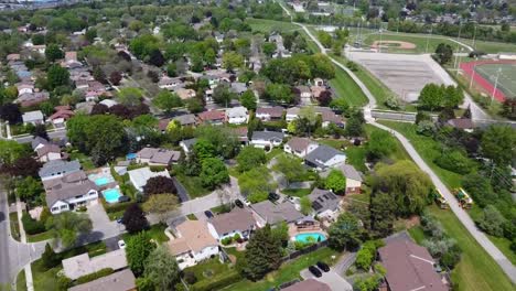 Drone-Inclinándose-Hacia-Abajo-Sobre-El-Vecindario-De-Burlington-Junto-A-Una-Pista-Escolar
