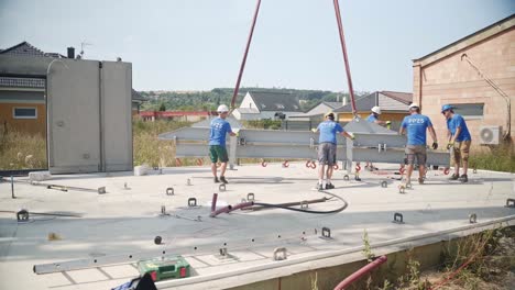 Trabajadores-De-La-Construcción-Instalando-Una-Viga-De-Metal-En-Una-Plataforma-De-Construcción-De-Hormigón