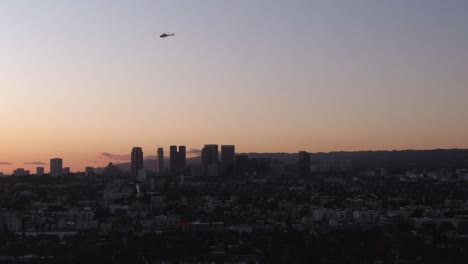 Helicopter-flyover-Los-Angeles-Downtown-skyline-during-sunset,-Aerial-Descending-shot