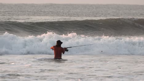 Person-fishing-on-the-shore-in-water-with-quite-a-lot-of-waves-in-Mexico