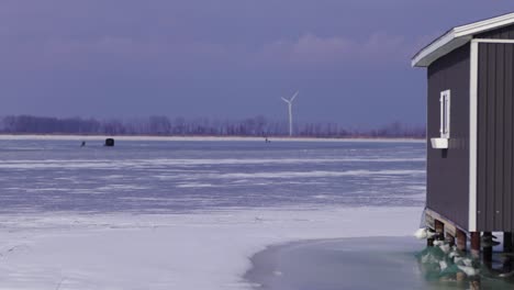 Frozen-lake-hut,-ice-fishing,-Canada,-windmill,-fishing-tent-on-frozen-lake,-Canada,-USA