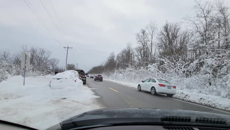 Dashcam-footage-of-a-tow-truck-driver-shoveling-snow-from-around-a-motor-vehicle-on-the-side-of-the-road-during-a-recovery-after-a-blizzard-in-Fort-Erie,-Ontario-Canada