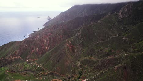 Aerial-reveal-of-green-volcanic-coast-with-mountain-ridge,-Tenerife