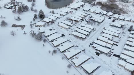 Aerial-shot-of-retirement-homes-overlooking-a-golf-course-covered-in-a-blanket-of-snow