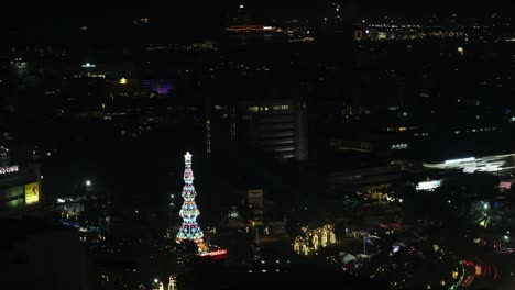 Timelapse-De-Movimiento-Del-Tráfico-En-El-Círculo-De-Fuente-Osmeña-Durante-La-Noche-Con-Un-Colorido-árbol-De-Navidad-Brillando-En-La-Oscuridad-En-La-Ciudad-De-Cebú,-Filipinas