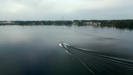 Ski-boat-driving-on-calm-lake-in-Winter-Haven-Florida-in-winter-on-an-overcast-day