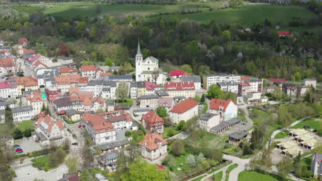 Aerial-view-of-old-European-town-with-central-Catholic-Church-and-tenements-surrounded-by-green-hills