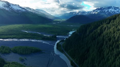 Aerial-View-Of-Resurrection-River-Surrounded-By-Lush-Forest-And-Snow-capped-Mountains-On-The-Kenai-Peninsula-In-Alaska