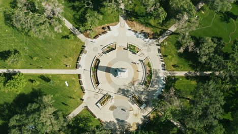 Luftaufnahmen-über-Einem-Park-Mit-Einem-Platz-Und-Einem-Denkmal-In-Der-Mitte-Mit-Symmetrischen-Wegen-Und-Einer-Gehenden-Person