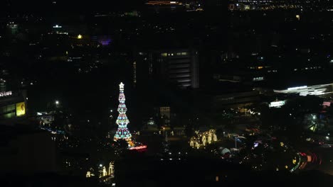 Bewegungszeitraffer-Des-Verkehrs-Am-Fuente-Osmeña-Circle-Bei-Nacht-Mit-Buntem-Weihnachtsbaum,-Der-Im-Dunkeln-In-Cebu-City,-Philippinen,-Funkelt