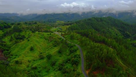 Aerial-view-of-a-winding-tropical-mountain-road-with-misty-clouds-in-the-background