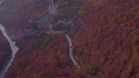Road-leading-into-mountain-tunnel-during-fall-season-in-Montenegro,-aerial