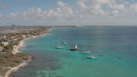 Drone-shot-of-ships-and-blue-ocean-in-Aruba,-Caribbean-with-spectacular-view-of-coastline