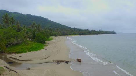 Drone-traveling-forward,-capturing-the-stormy-beauty-of-a-deserted-tropical-shoreline-during-a-rainy-day