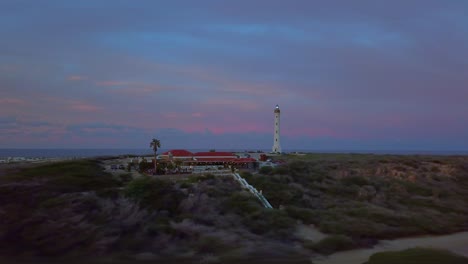 Drone-shot-of-California-light-house-and-restaurant-in-Aruba,-Caribbean-with-spectacular-sunset